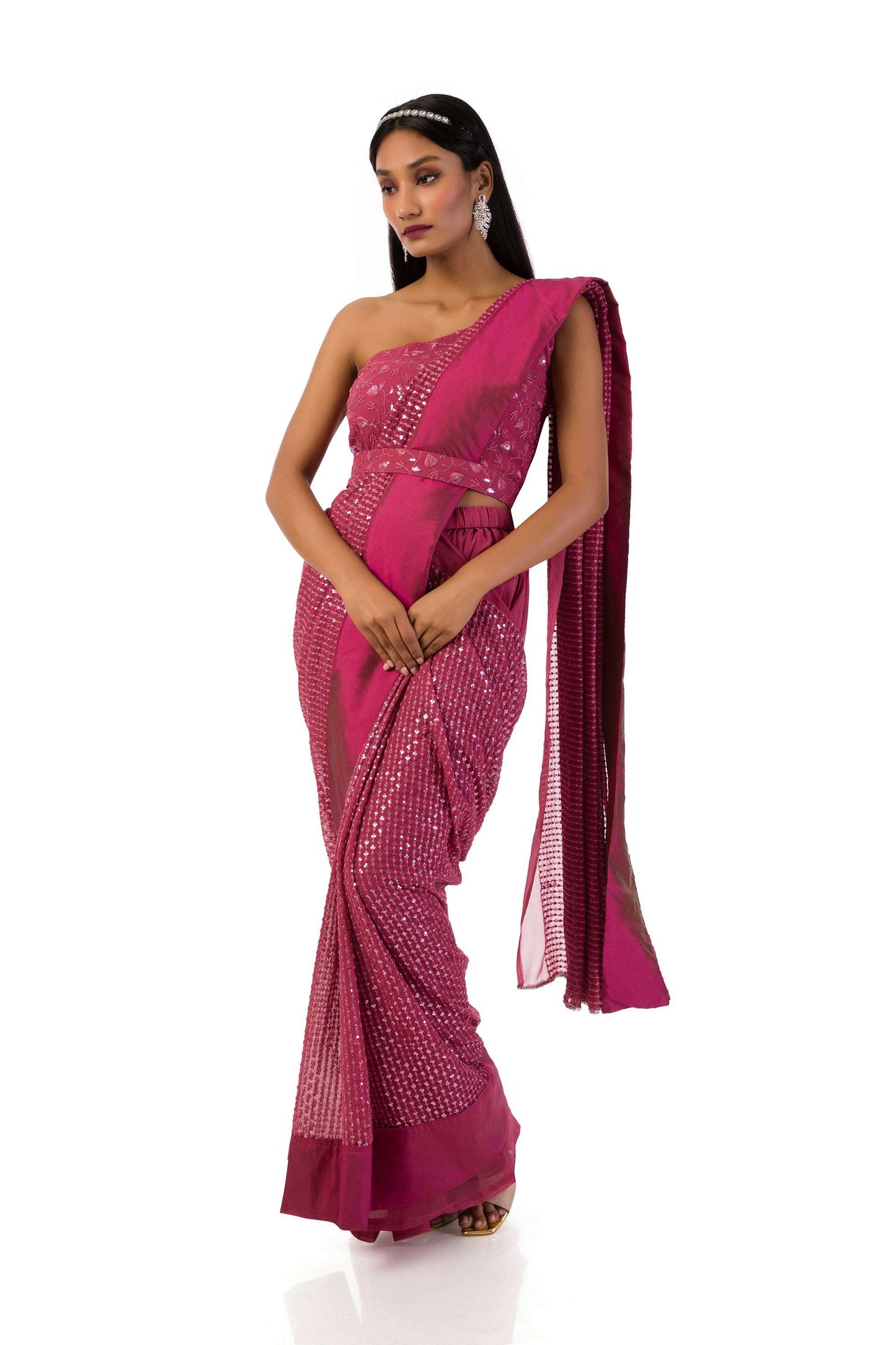 Woman wearing a dust pink one-shoulder blouse with sequins and thread work, paired with palazzo pants and a stitch-ready-to-wear saree drape, and a matching belt.