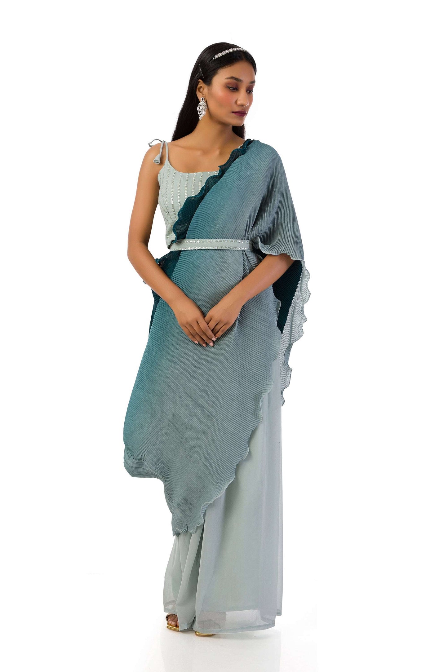 Model wearing an ash grey blouse with sequences and thread work, elasticated palazzo pants, stitched saree drape with side pleats, and a matching belt.