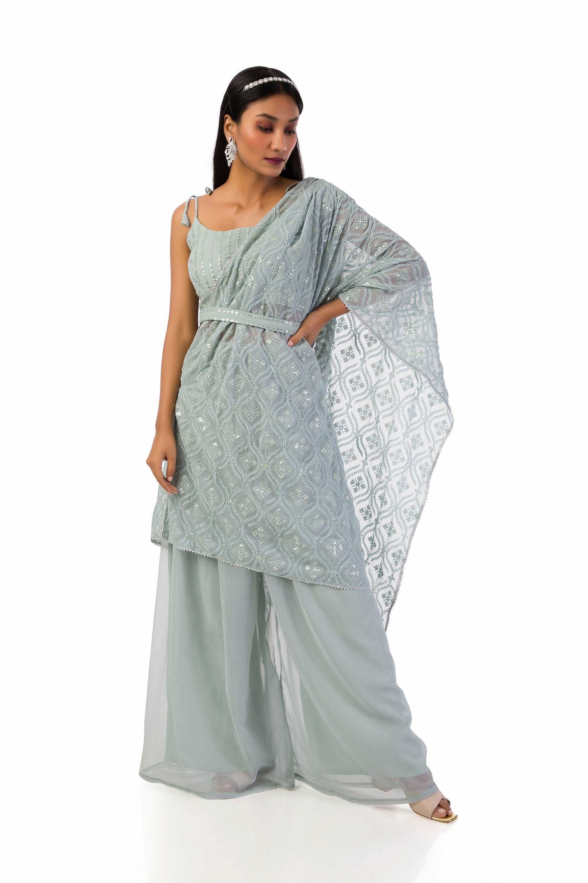 Model wearing an ash grey blouse with intricate sequences and thread work, paired with palazzo pants and a stitched dupatta drape, accessorized with a matching belt