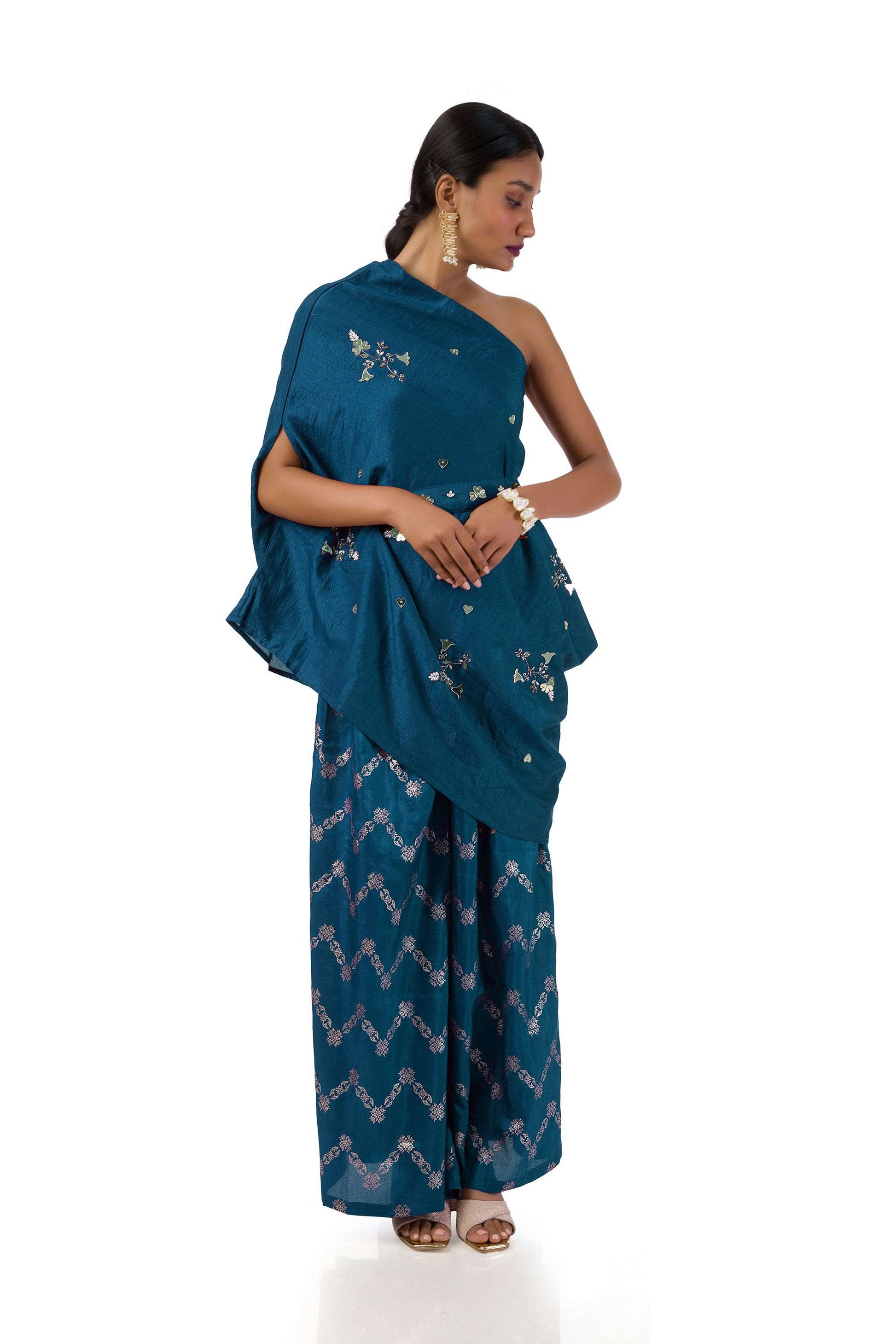 Woman wearing a Dark Blue One-Shoulder Draped Top with Golden Printed Palazzo Pants and matching belt, featuring semi-silk base and hand embroidery.