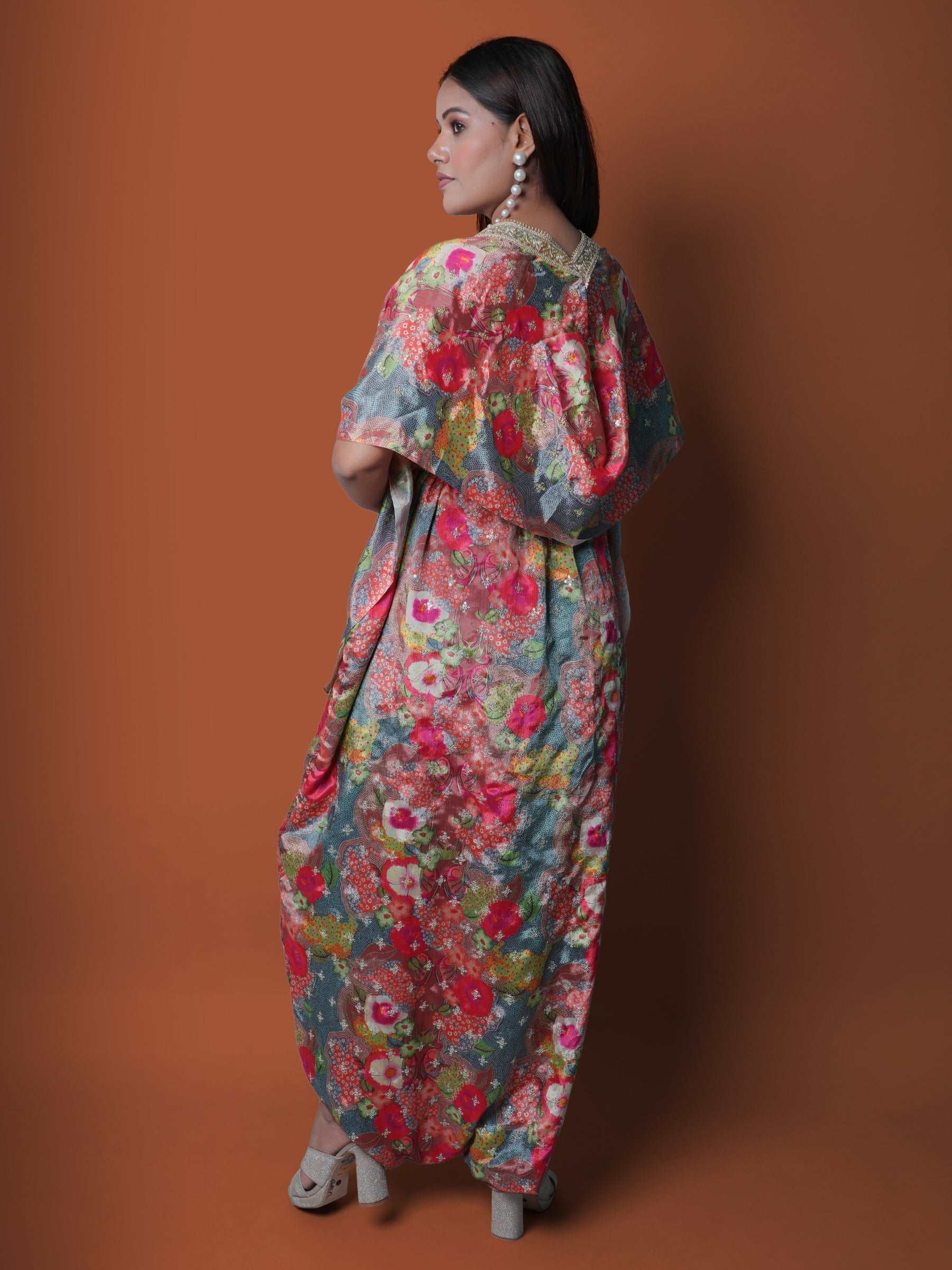 Woman wearing a floral printed strapless jumpsuit, paired with a matching cape and embroidered belt