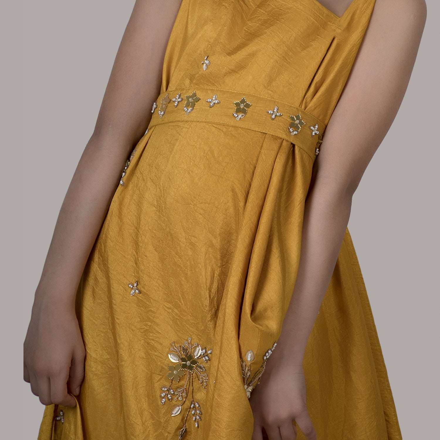 Girl wearing a mustard draped side cowl neck dress with hand embroidery and a matching belt